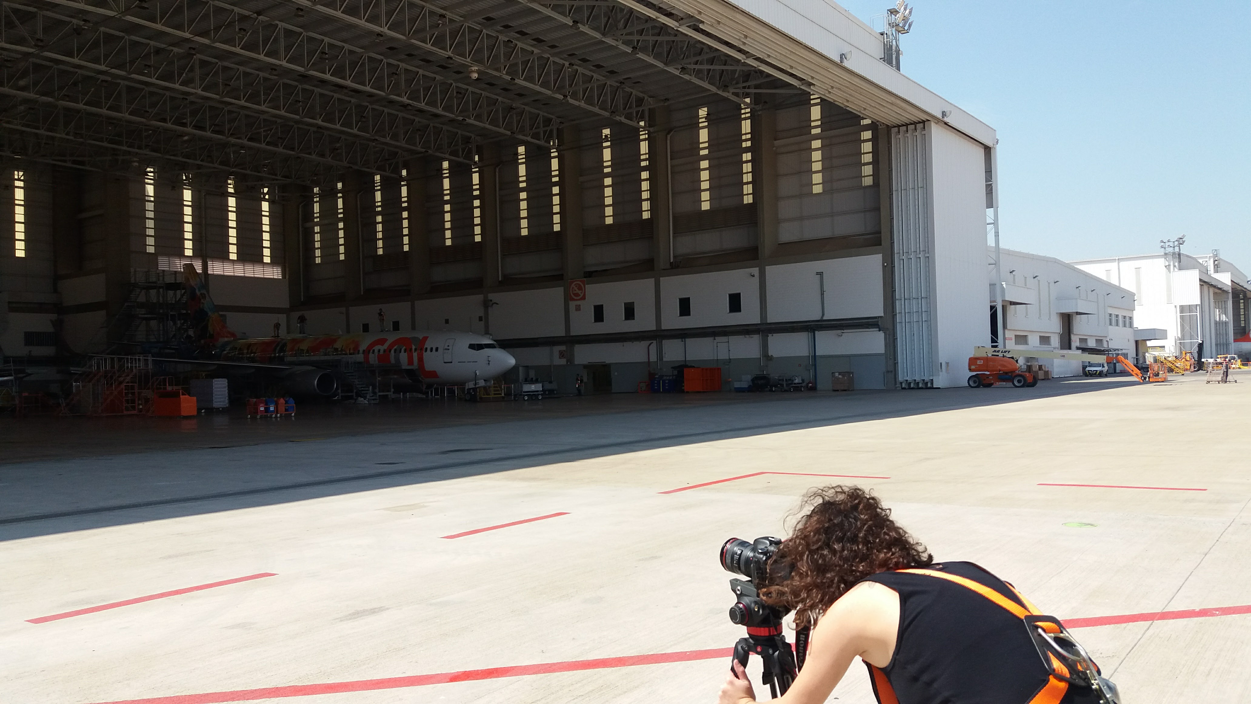 mulher filmando num hangar para produzir conteúdo para campanhas de marketing digital e tráfego pago. Ela trabalha para a produtora de vídeo